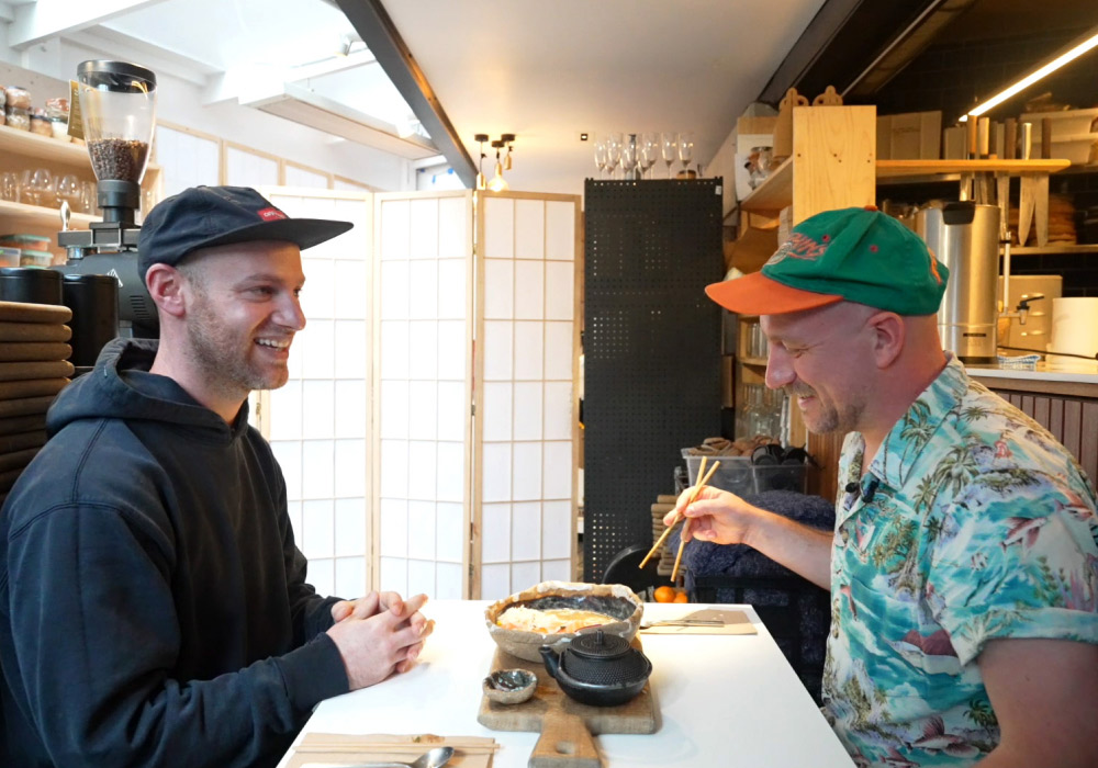 2 men sitting down in Japanese restaurant chatting and smiling