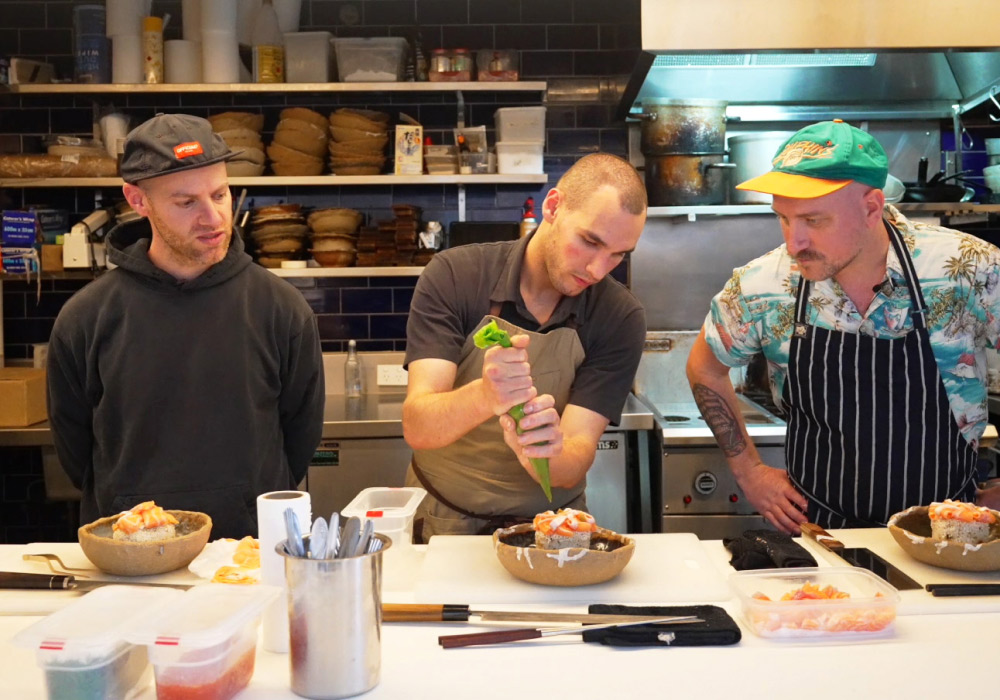 Head chef teaching 2 men how to assemble a plate in Japanese Restaurant, Tento