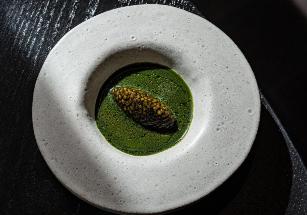 A wide rimmed slate bowl filled with a green soup