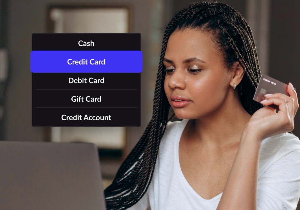 Person holding a credit card in front of a laptop.