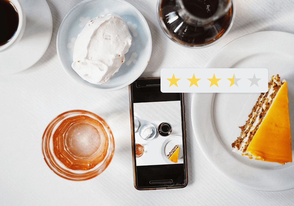 Cake, ice cream, syrup, a glass of water and a phone viewed from a above on a white table
