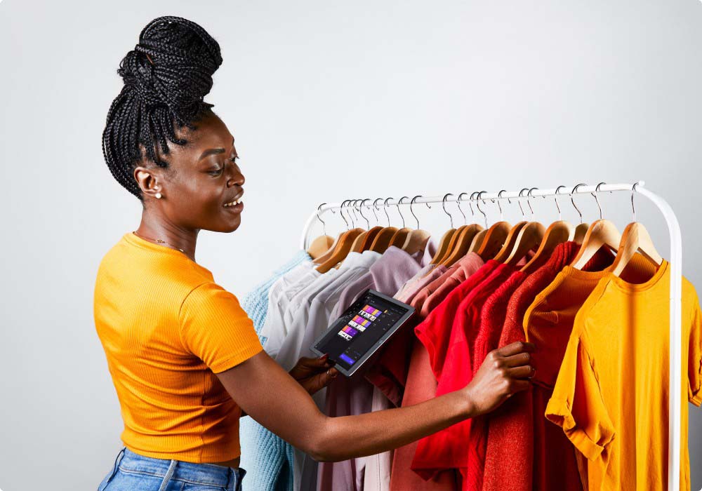 Smiling woman with clothing rack of t-shirts
