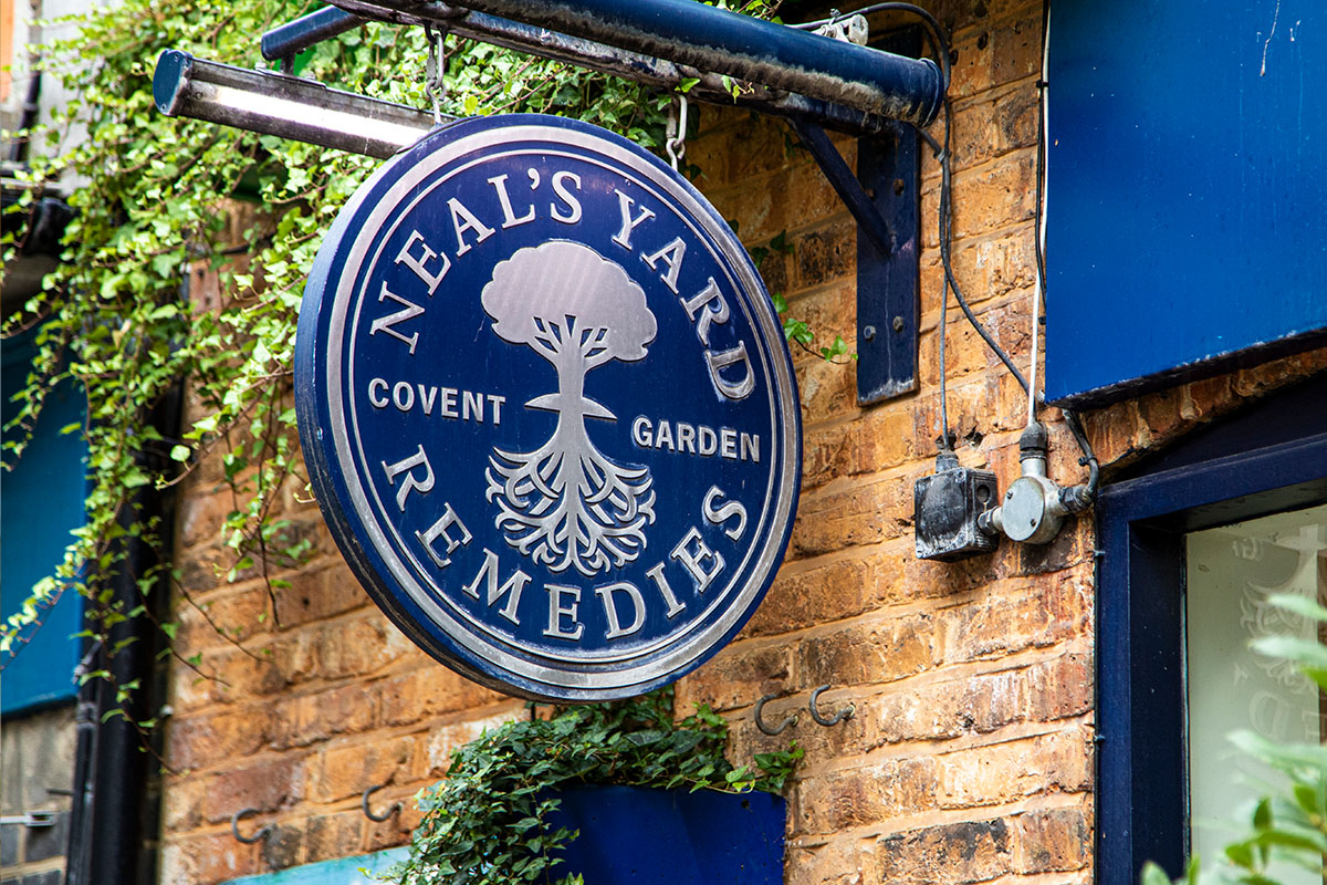 A round blue sign that reads 'Neal's Yard Remedies' is hanging outside a shop