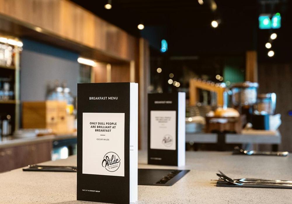 A hotel restaurant with black menus stood up on the table