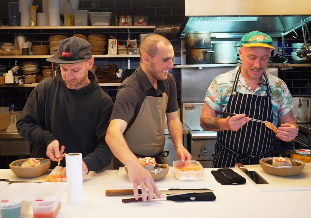 Three chefs cooking at TenTo and laughing with head chef