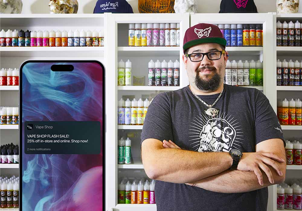 vape shop employee, in the foreground iPhone showing notification from vape webshop