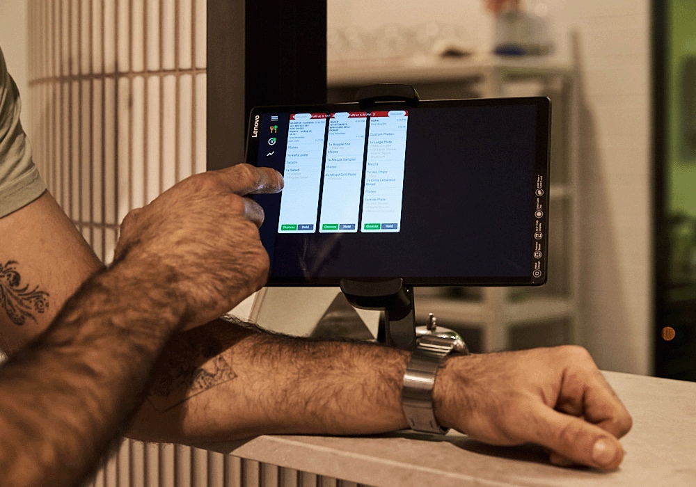 Arm pointing at iPad kitchen dockets for restaurant back of house