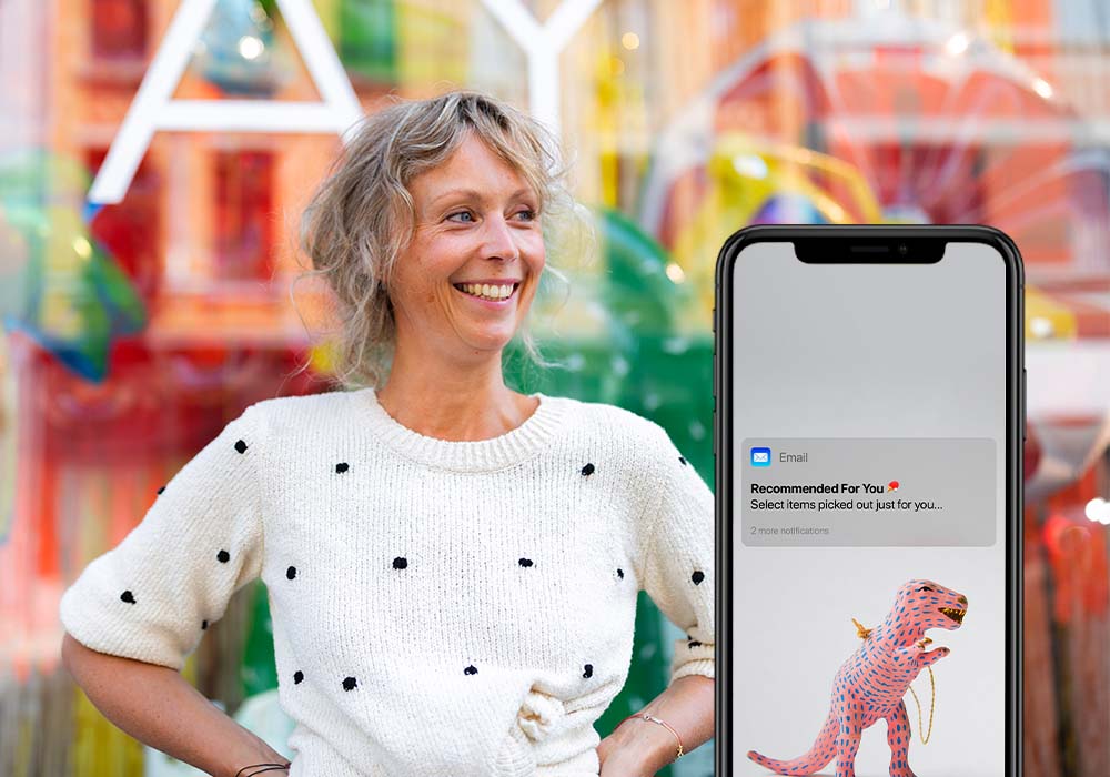 Smiling retailer, iPhone with loyalty notification on it's screen shown in the foreground