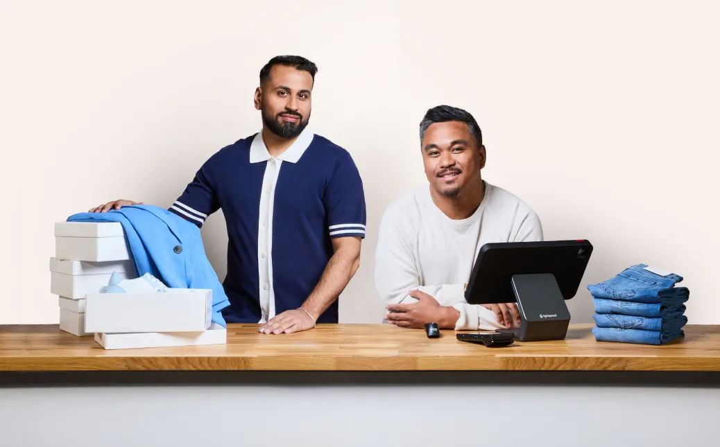 Two people standing behind a retail store counter with Lightspeed point of sale hardware.