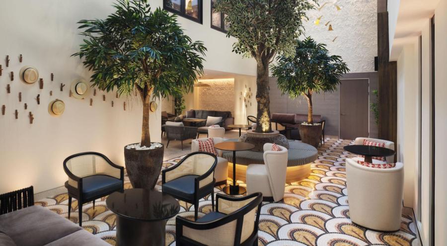 A hotel lobby with black tables and olive trees