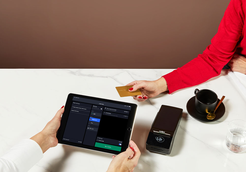 hands paying with card at a payment terminal. Lightspeed ePOS screen in bottom left corner