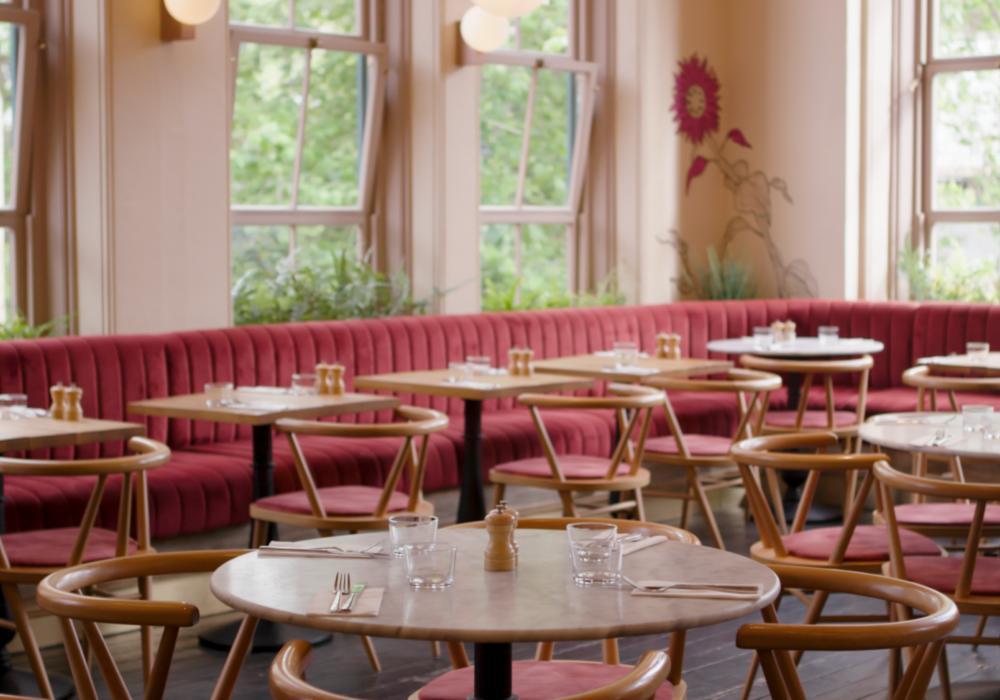 A dining room with wooden tables and chairs and red booth seating