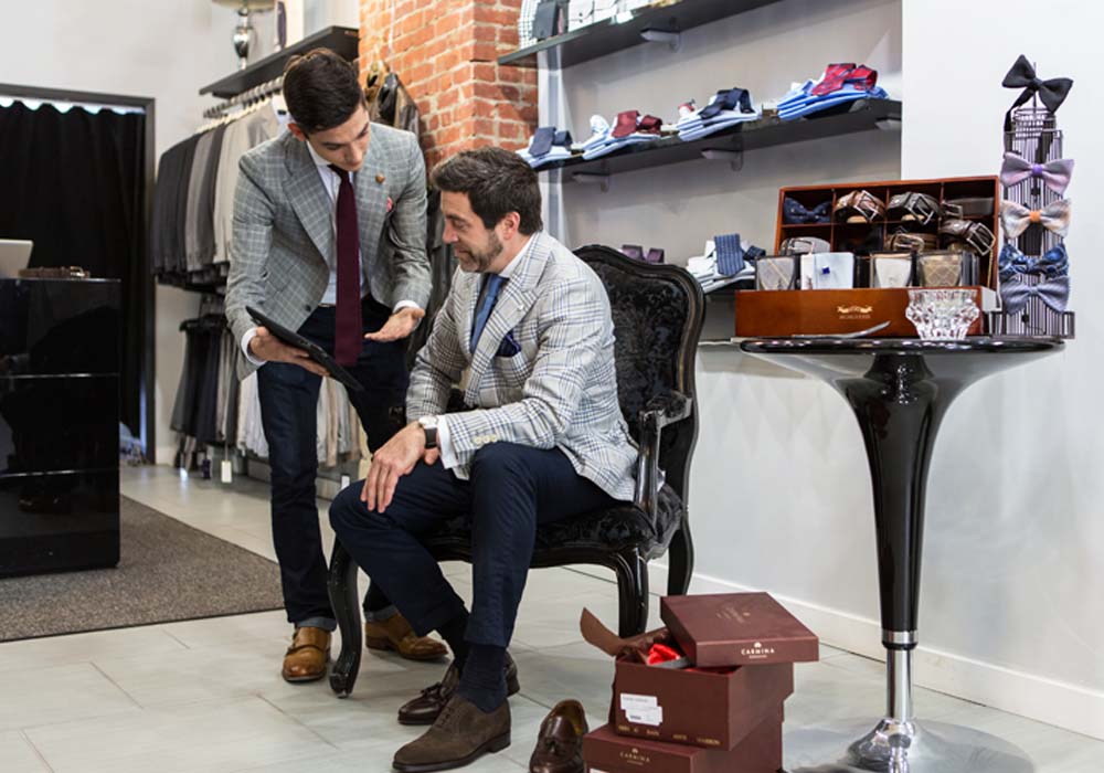 Retailer showing a customer products on an iPad in a men's apparel store