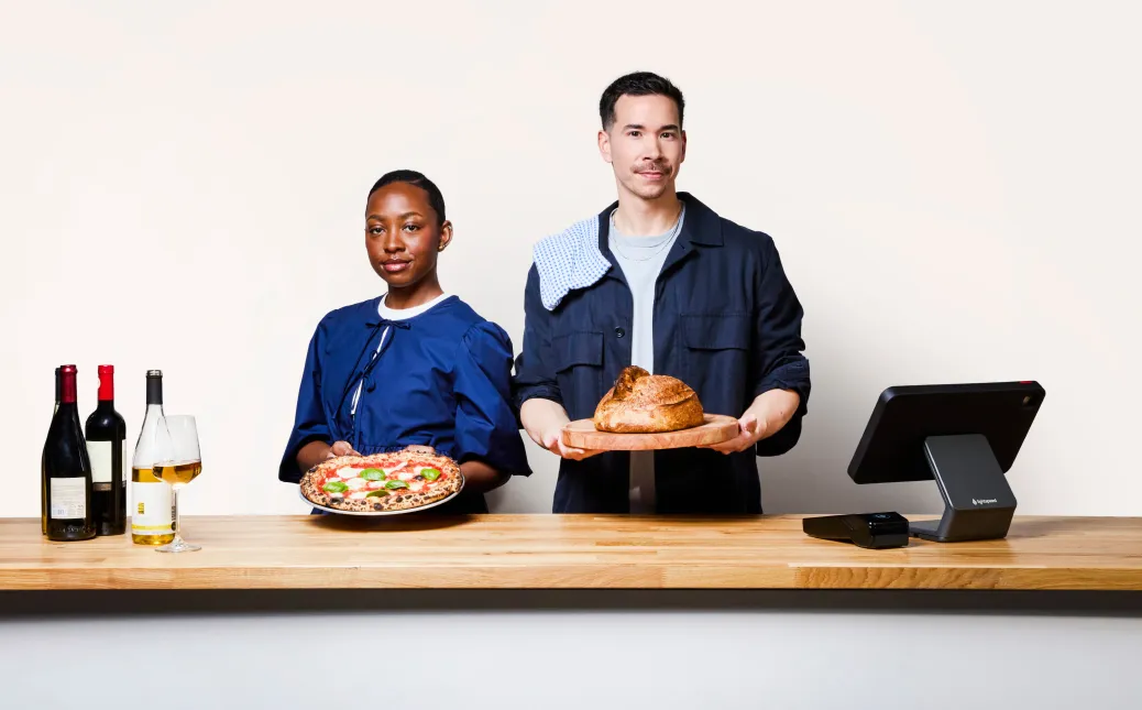 Two people standing at a restaurant counter with Lightspeed point of sale hardware.