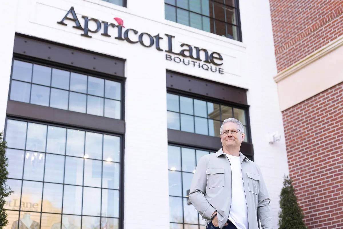 A man stands in front of a retail storefront.