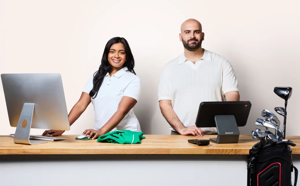 Two people standing behind the counter at a golf pro shop.