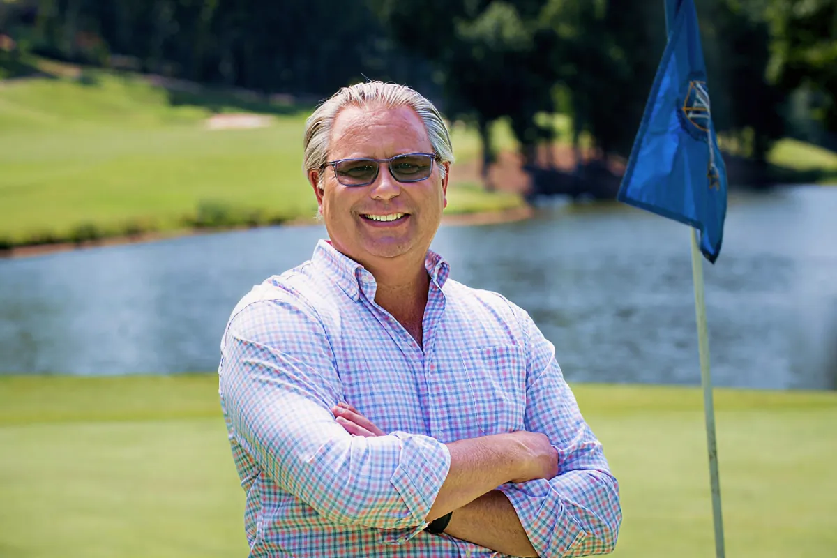 A man grins at a golf course.