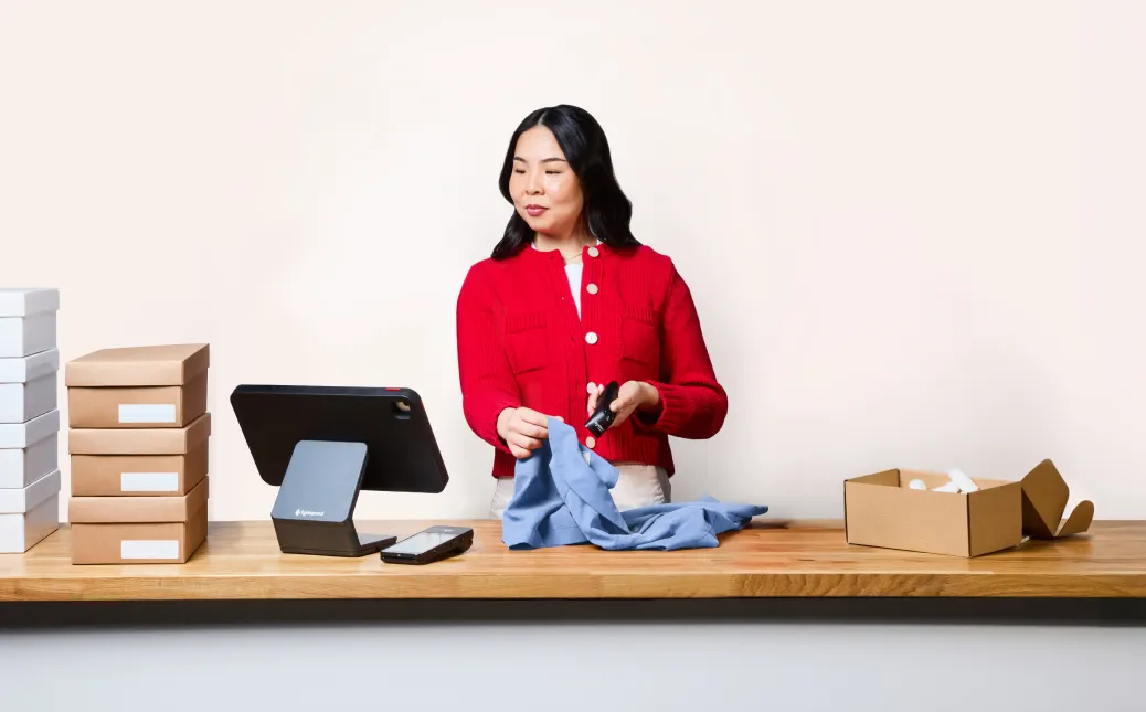 A woman scans a shirt behind the counter at a retail store.