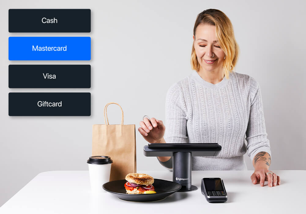 Person using Lightspeed ePOS next to payment types and food packaging
